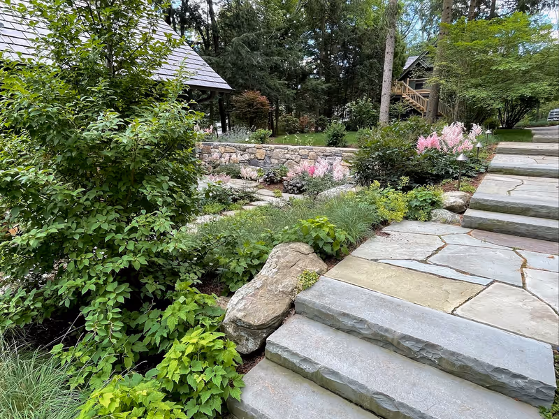 Broad stone steps between planted terraces and boulders.