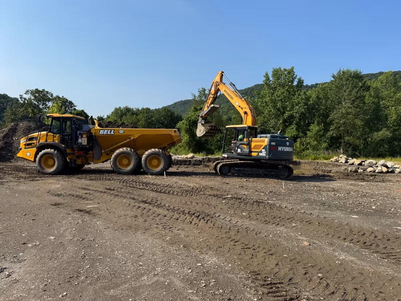 Excavator loading earth into an articulated hauler.