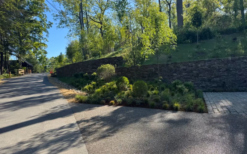 Managed property road, stone wall, and planted grounds maintained for estate-level presentation.