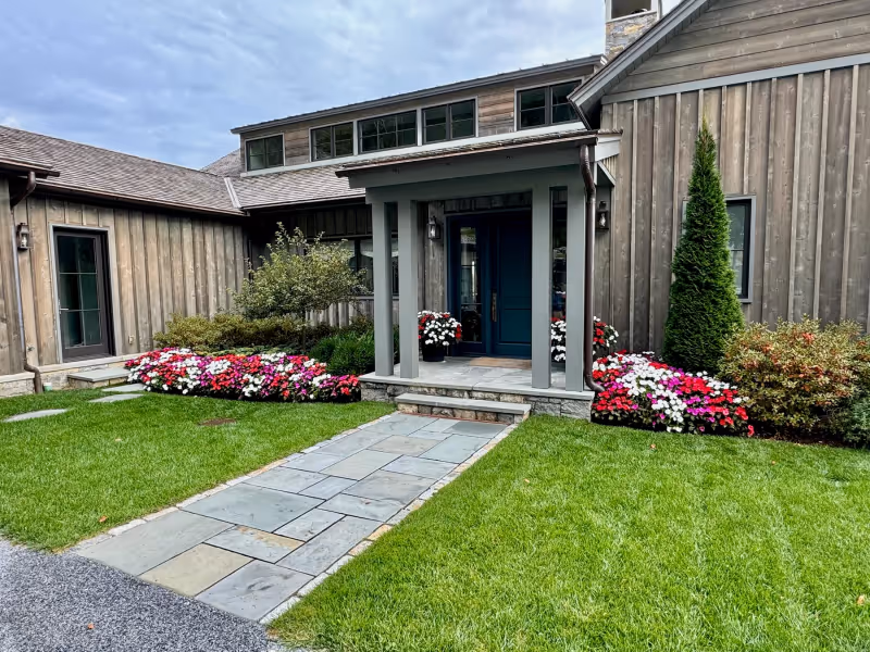 Seasonal flower plantings and maintained lawn around a residential front entry.