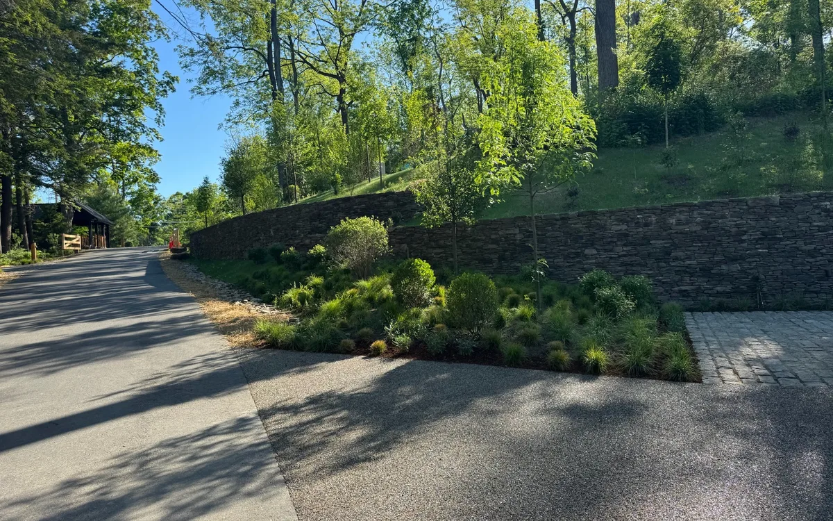 Managed property road, stone wall, and planted grounds maintained for estate-level presentation.