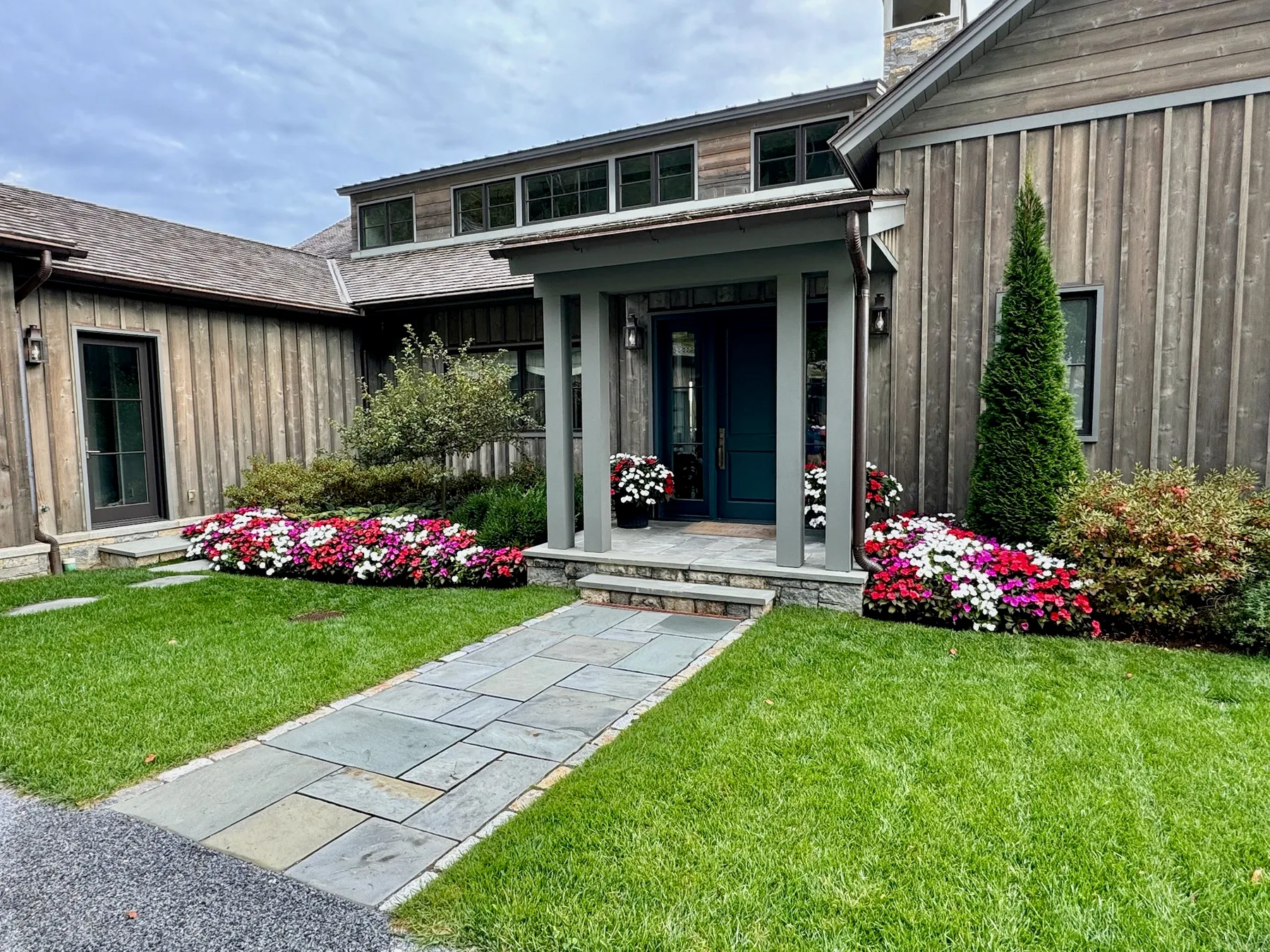 Seasonal flower plantings and maintained lawn around a residential front entry.